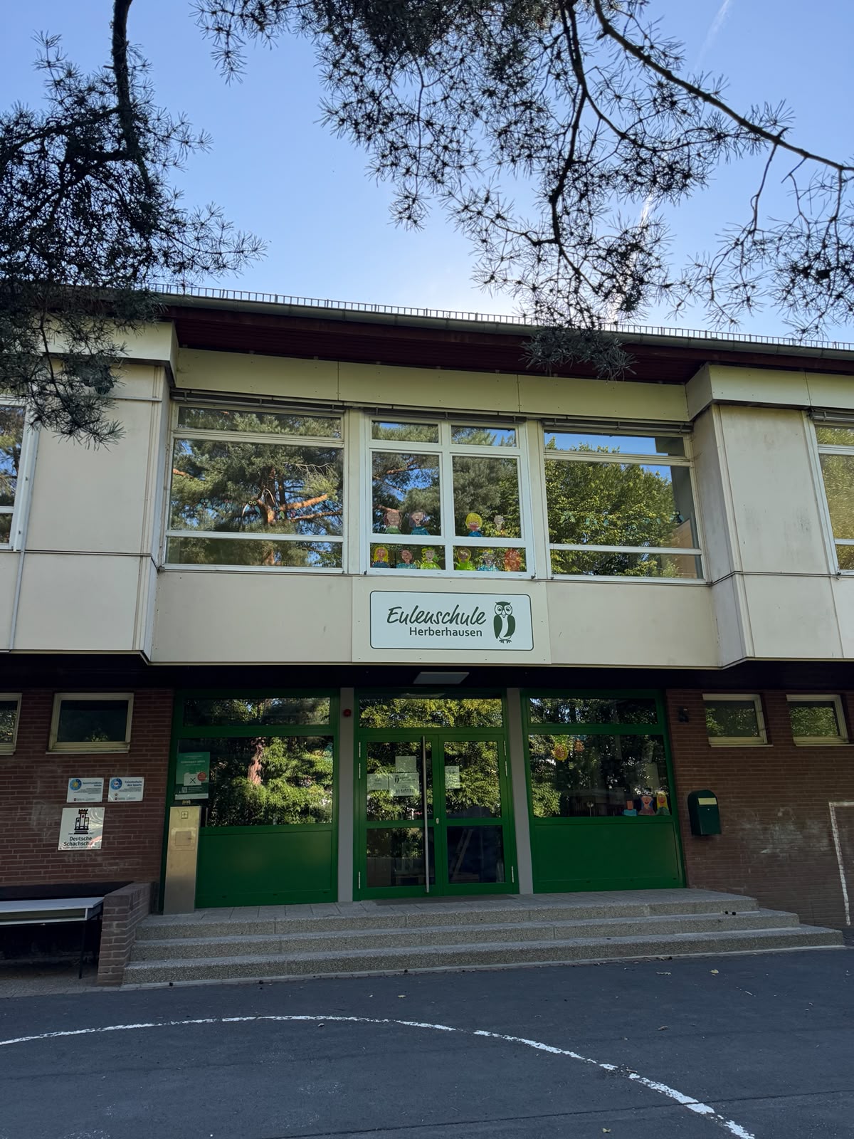 Haupteingang der Eulenschule Herberhausen mit grünen Türen und Schullogo über dem Eingang